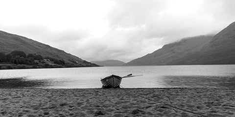 A single boat sits on the sand in the rain at Lough Nafooey in County Galway. Lough Nafooey is a rectangular shaped glacial lake on the border of County Mayo and County Galway.