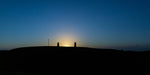 The sun begins too peep above the Hill of Tara between the Lia Fáil and the memorial headstone.