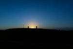 The sun begins too peep above the Hill of Tara between the Lia Fáil and the memorial headstone.