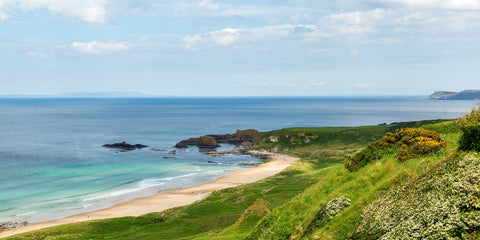A breathtaking view of White Park Bay in Antrim, with white sand, green grass and a blue sky. Heaven.